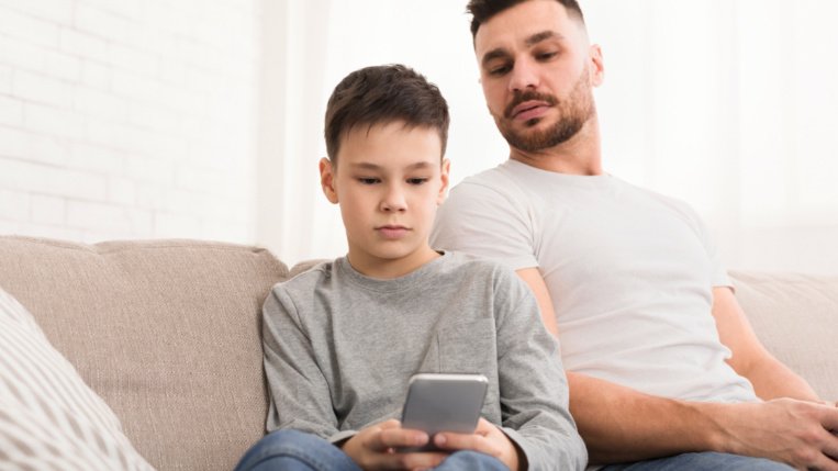 Elternteil schaut kritisch auf Kind am Handy